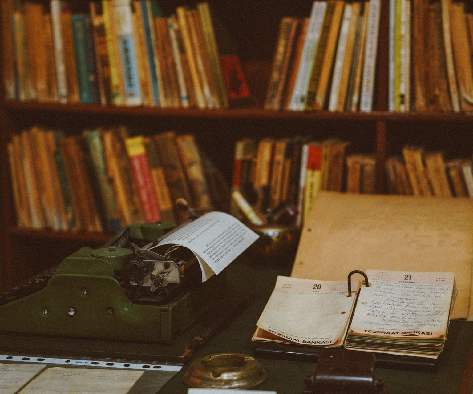 A cinematic still life of an open screenplay, leather notebook, fountain pen, index cards with story beats, and stacked craft books — the story creation journey.